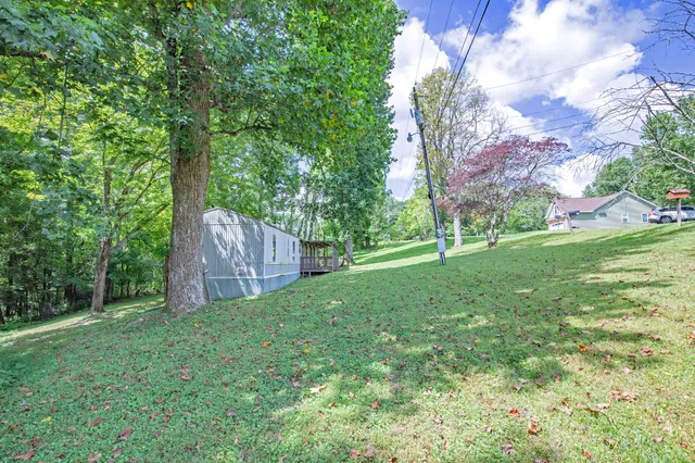 a view of a house with a big yard and large trees
