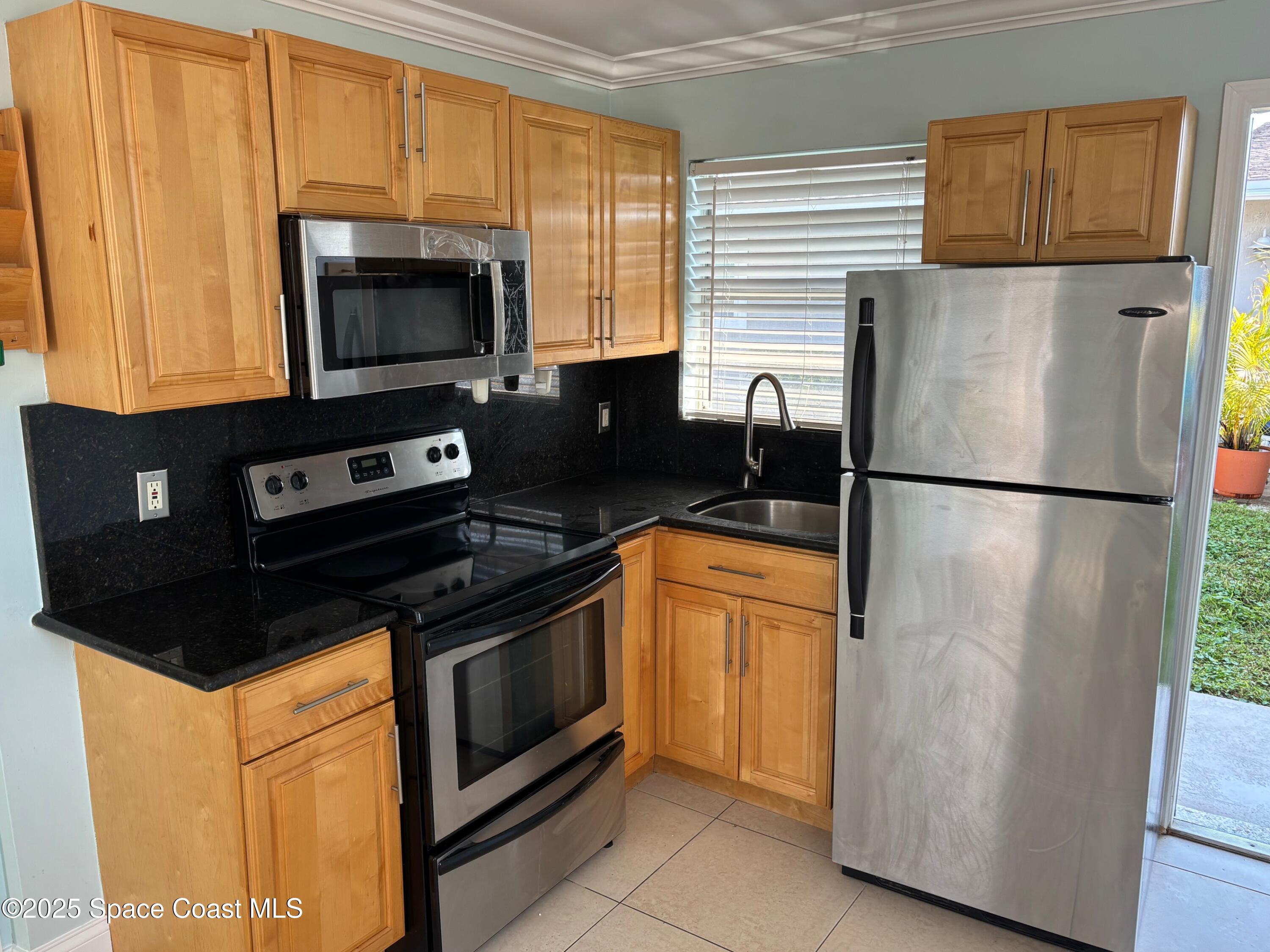 306 Johnson Avenue, Unit 5 Cape Canaveral, FL 32920 - Photo 11 of 17 a kitchen with stainless steel appliances granite countertop a stove top oven a refrigerator a sink and dishwasher
