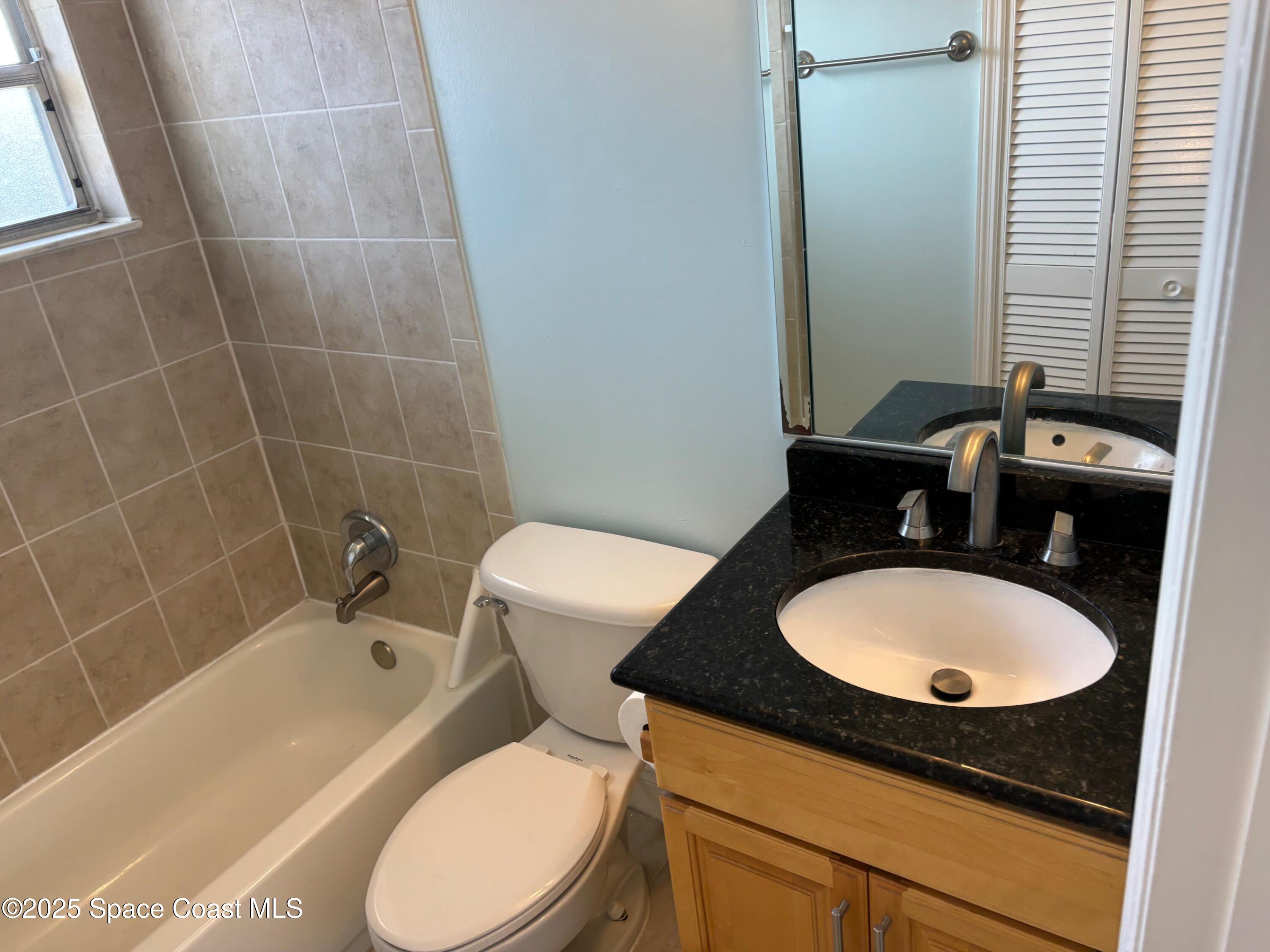 306 Johnson Avenue, Unit 5 Cape Canaveral, FL 32920 - Photo 15 of 17 a bathroom with a sink a toilet and mirror