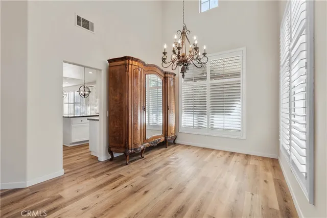 a view of a room with wooden floor chandelier and windows
