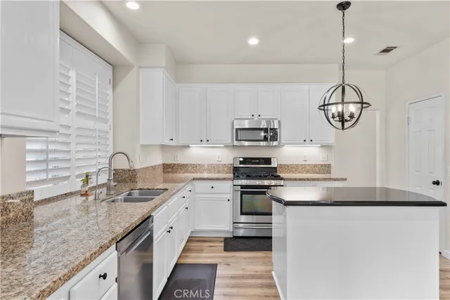 a kitchen with stainless steel appliances granite countertop a sink a stove and a wooden floors