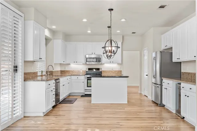 a large kitchen with stainless steel appliances kitchen island white cabinets and wooden floor