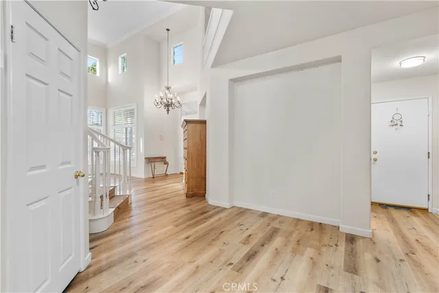 a view of a hallway with wooden floor and chandelier