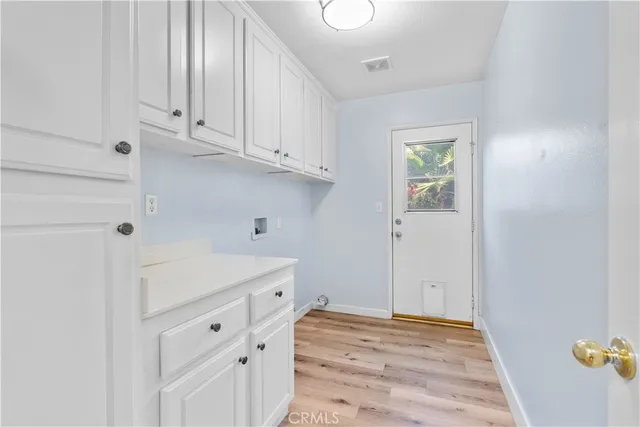 a view of a kitchen with white cabinets and wooden floor