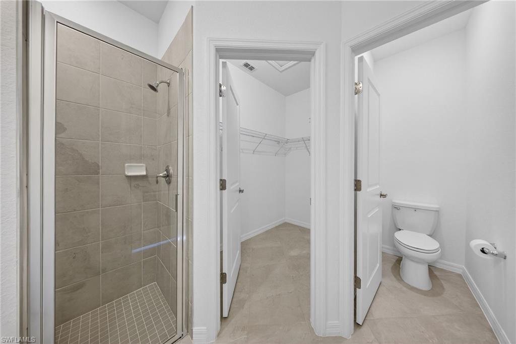 2220 Dragonfruit Way Naples, FL 34120 - Photo 13 of 31 Bathroom with a spacious closet, a shower stall, and light tile patterned floors