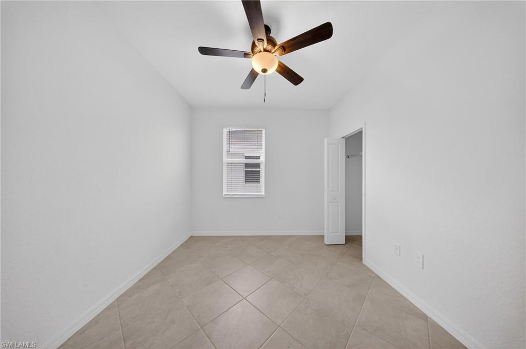 2220 Dragonfruit Way Naples, FL 34120 - Photo 18 of 31 Unfurnished bedroom featuring ceiling fan, light tile patterned flooring, and a spacious closet
