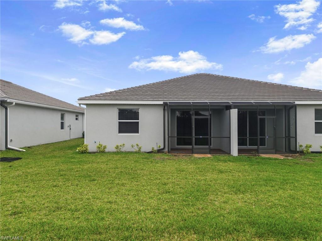2220 Dragonfruit Way Naples, FL 34120 - Photo 25 of 31 Back of house with a lawn, stucco siding, and a sunroom