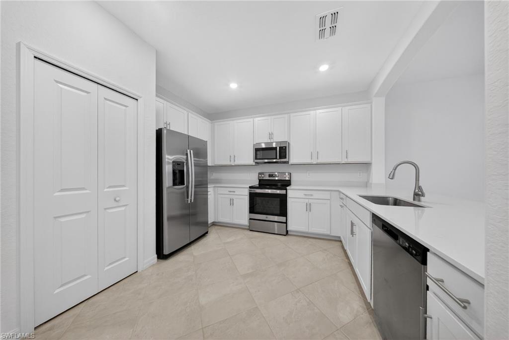 2220 Dragonfruit Way Naples, FL 34120 - Photo 3 of 31 Kitchen featuring stainless steel appliances, white cabinets, light stone counters, and recessed lighting
