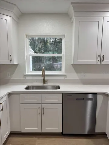 a kitchen with white cabinets and sink
