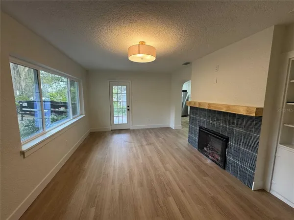 an empty room with wooden floor fireplace and windows