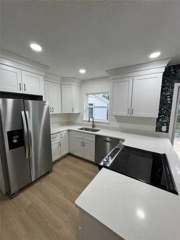 a kitchen with a refrigerator sink and cabinets