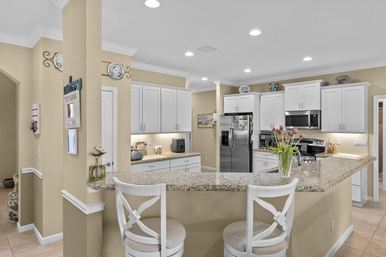 2190 Northwest Dalea Way Stuart, FL 34994 - Photo 6 of 31 a kitchen with stainless steel appliances kitchen island granite countertop a refrigerator and microwave