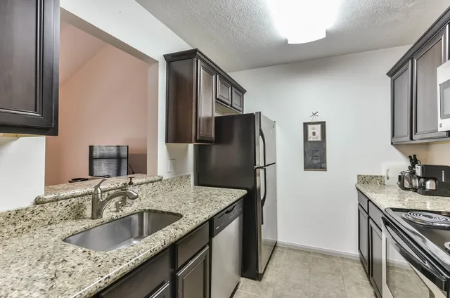 a kitchen with stainless steel appliances granite countertop a sink stove and refrigerator