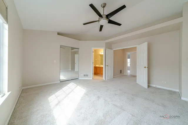 an empty room with chandelier fan and windows