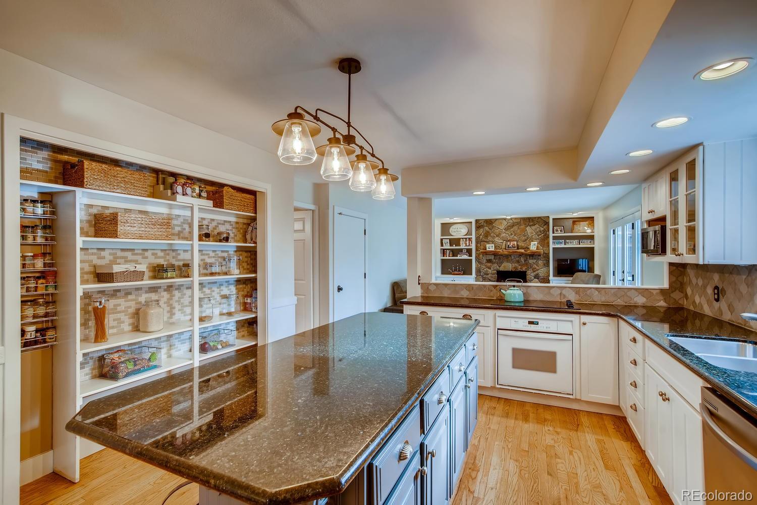 1894 La Quinta Circle Evergreen, CO 80439 - Photo 13 of 36 a kitchen with stainless steel appliances granite countertop a stove top oven a sink a dining table and chairs with wooden floor