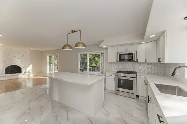 a large kitchen with stainless steel appliances granite countertop a stove a sink and a microwave