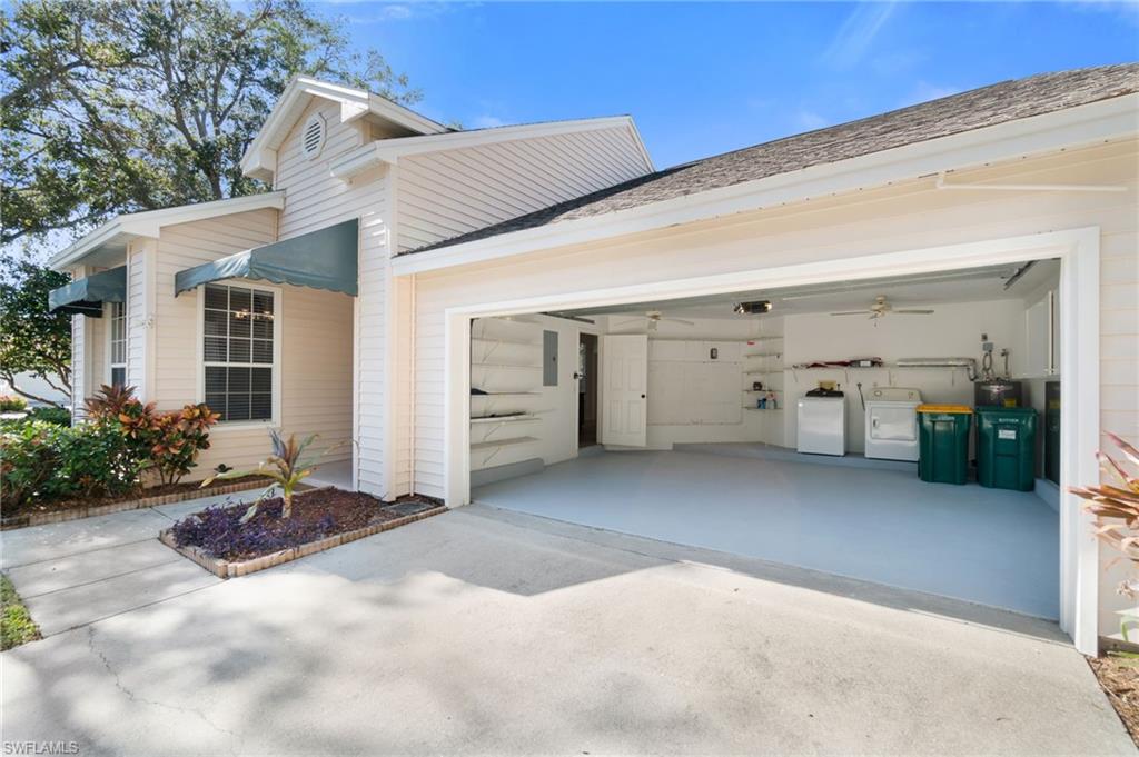 2662 Aft Avenue Naples, FL 34109 - Photo 15 of 26 View of side of property featuring driveway, a garage, and washing machine and clothes dryer