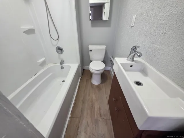 a bathroom with a granite countertop toilet a sink and a shower