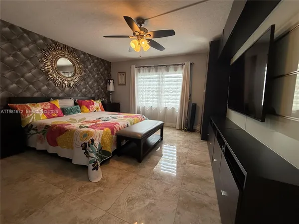 a bedroom with a bed and a flat tv screen on dresser