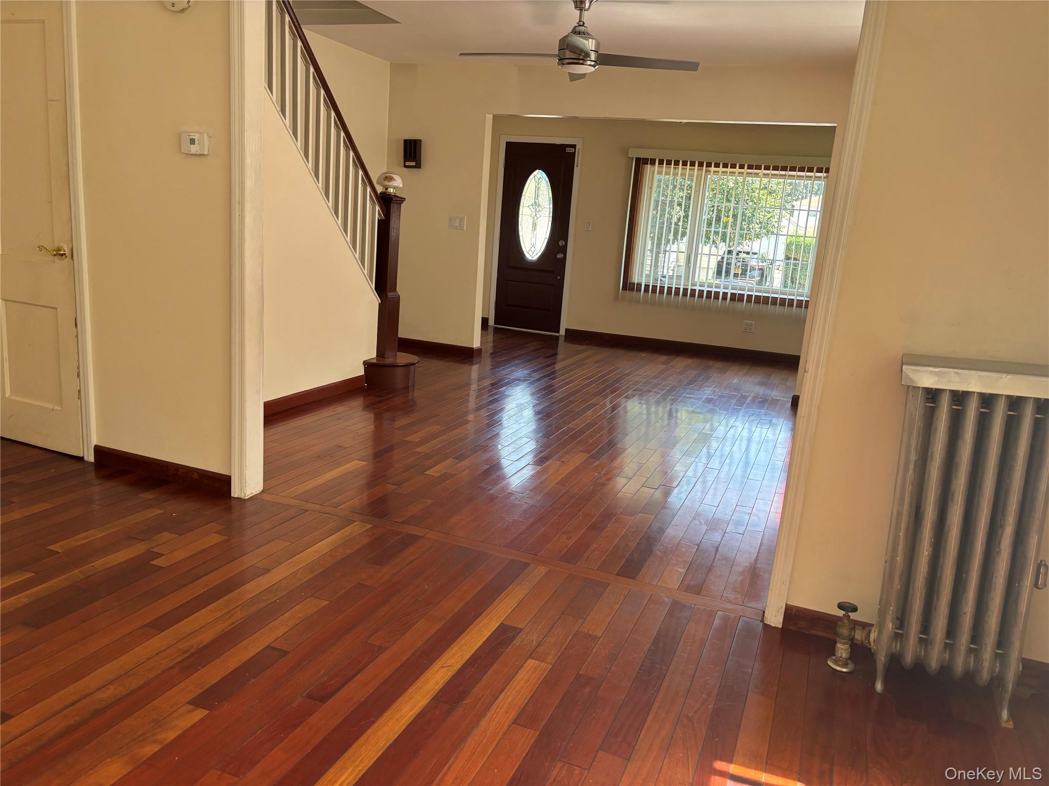 104-18 216th Street Queens, NY 11429 - Photo 14 of 49 Entryway featuring dark wood finished floors, stairs, radiator heating unit, and ceiling fan