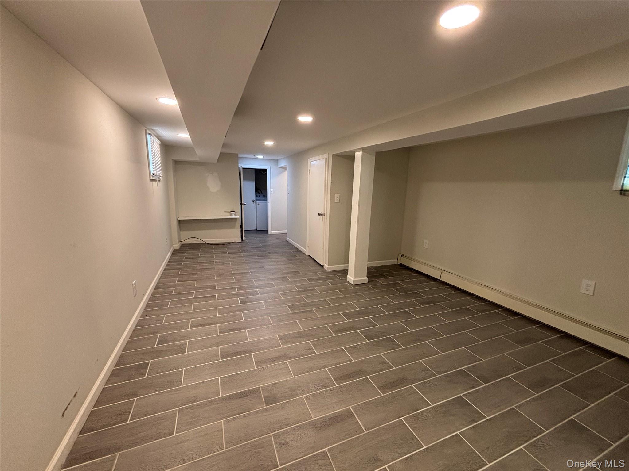 104-18 216th Street Queens, NY 11429 - Photo 25 of 49 Finished below grade area with recessed lighting, wood tiled floors, and a baseboard heating unit