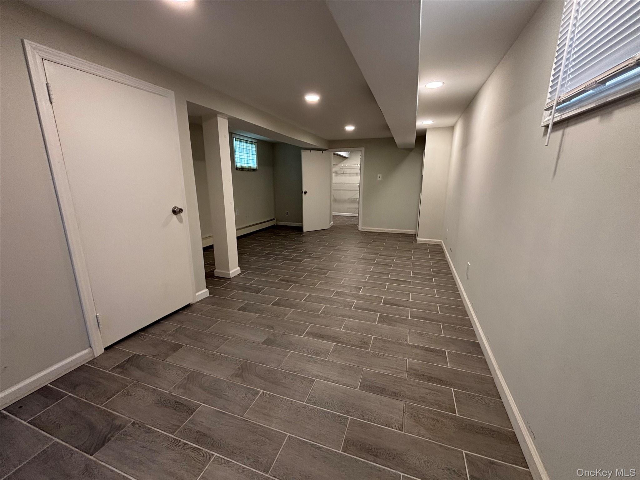104-18 216th Street Queens, NY 11429 - Photo 26 of 49 Basement featuring wood finish floors, recessed lighting, and a baseboard radiator