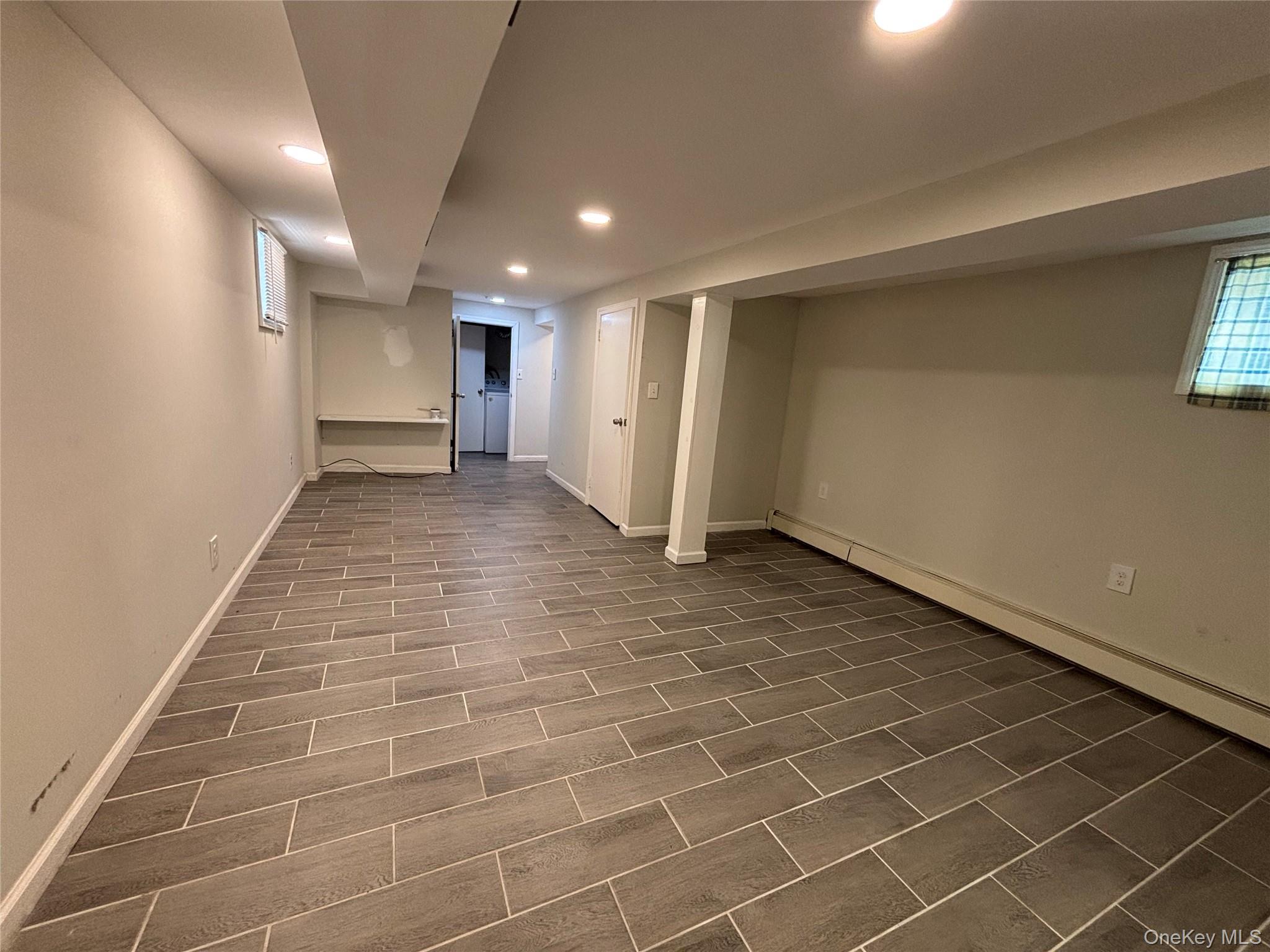104-18 216th Street Queens, NY 11429 - Photo 27 of 49 Basement featuring recessed lighting, dark wood-style flooring, and a baseboard heating unit