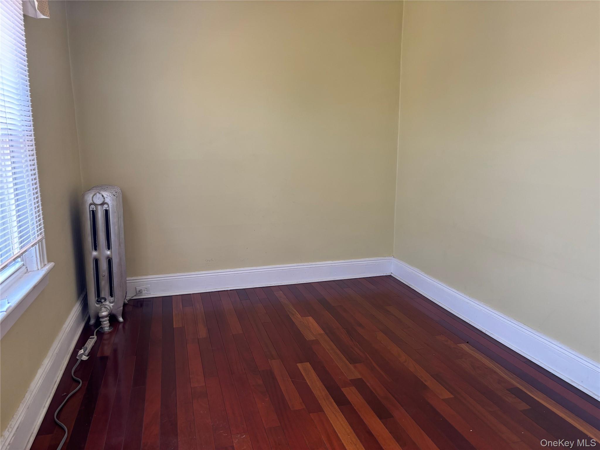 104-18 216th Street Queens, NY 11429 - Photo 33 of 49 Spare room featuring dark wood-type flooring and radiator
