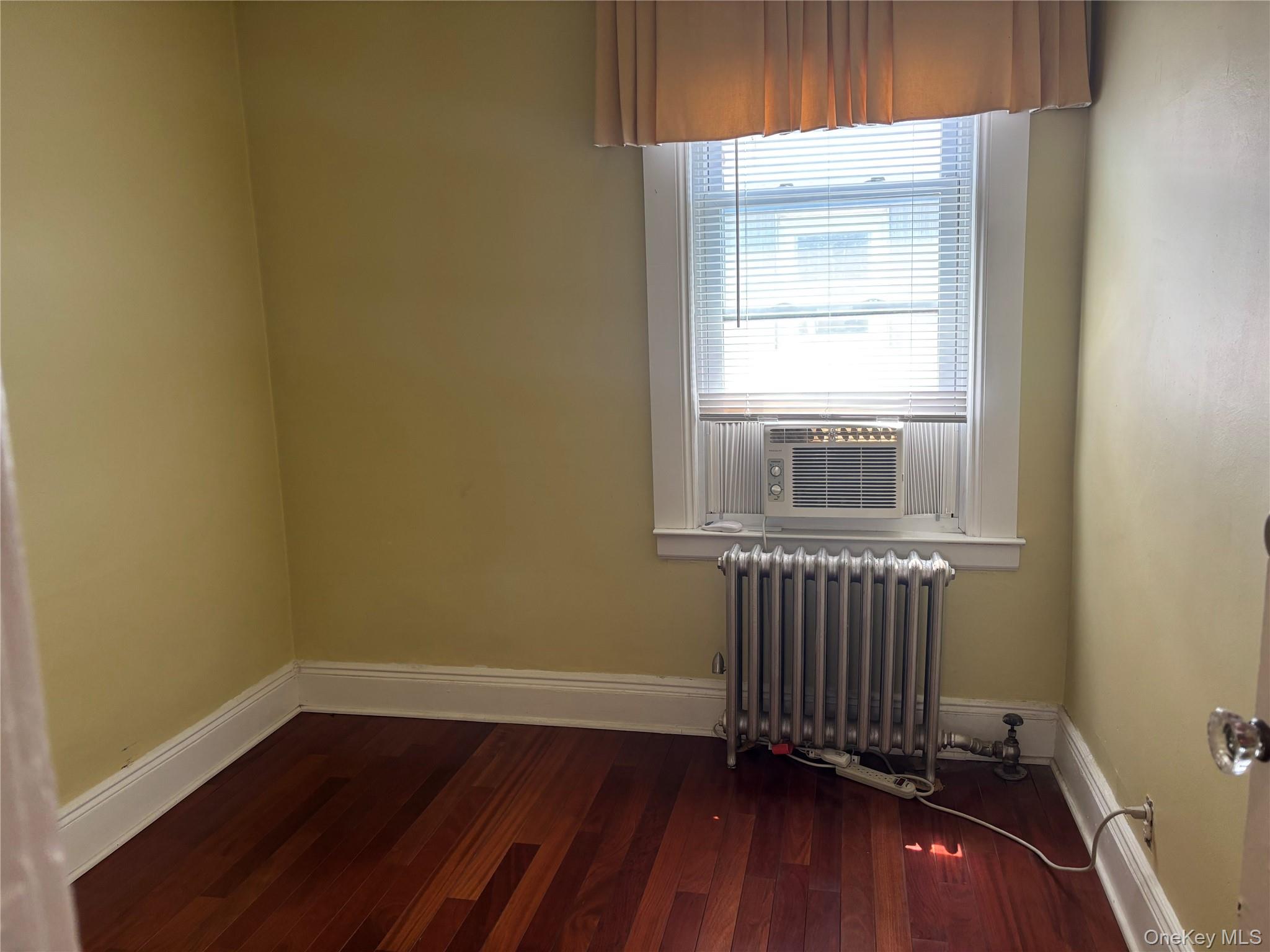 104-18 216th Street Queens, NY 11429 - Photo 37 of 49 Empty room with dark wood-type flooring, radiator, and cooling unit