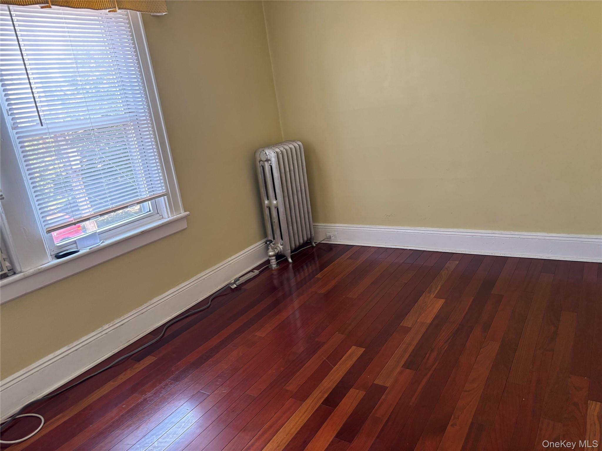 104-18 216th Street Queens, NY 11429 - Photo 39 of 49 Spare room featuring radiator heating unit and dark wood-style flooring