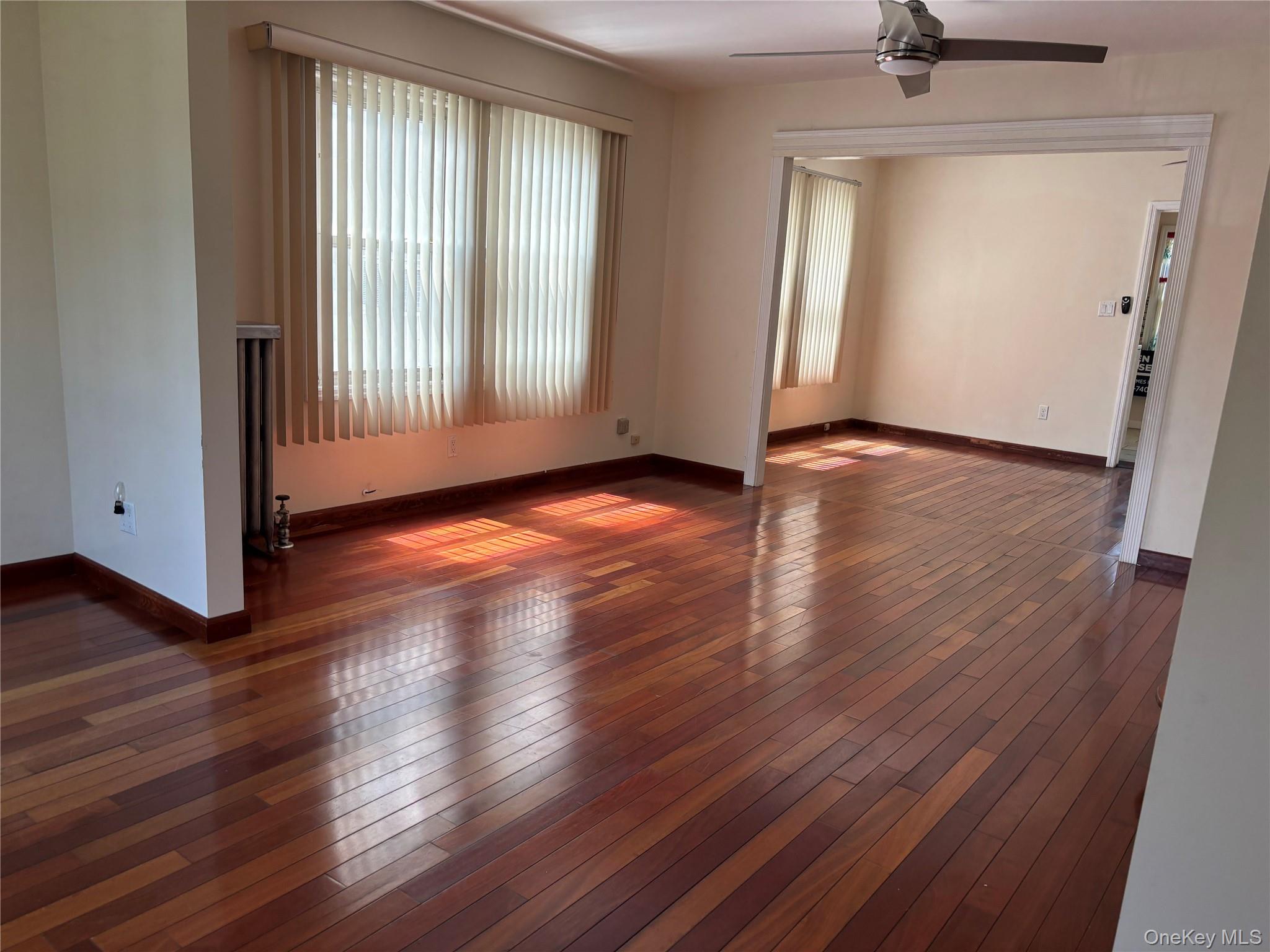 104-18 216th Street Queens, NY 11429 - Photo 9 of 49 Unfurnished living room featuring ceiling fan, dark wood-style floors, and radiator heating unit