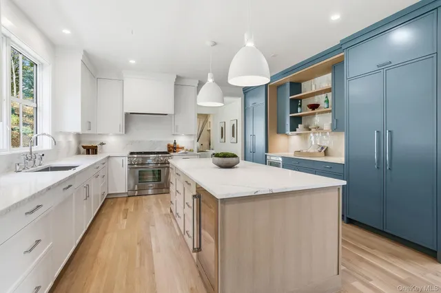 a large kitchen with stainless steel appliances a large counter top a stove and a sink