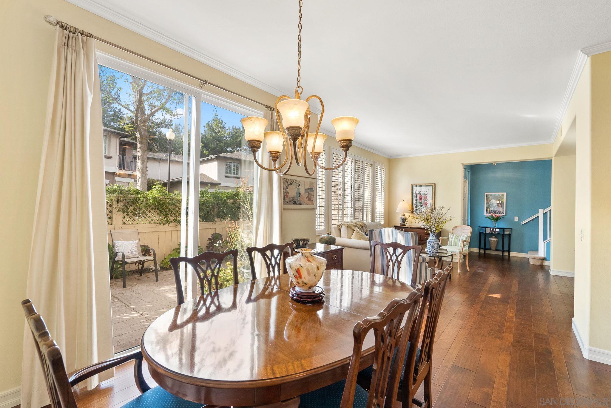 a dining room with wooden floor a chandelier a glass table and chairs