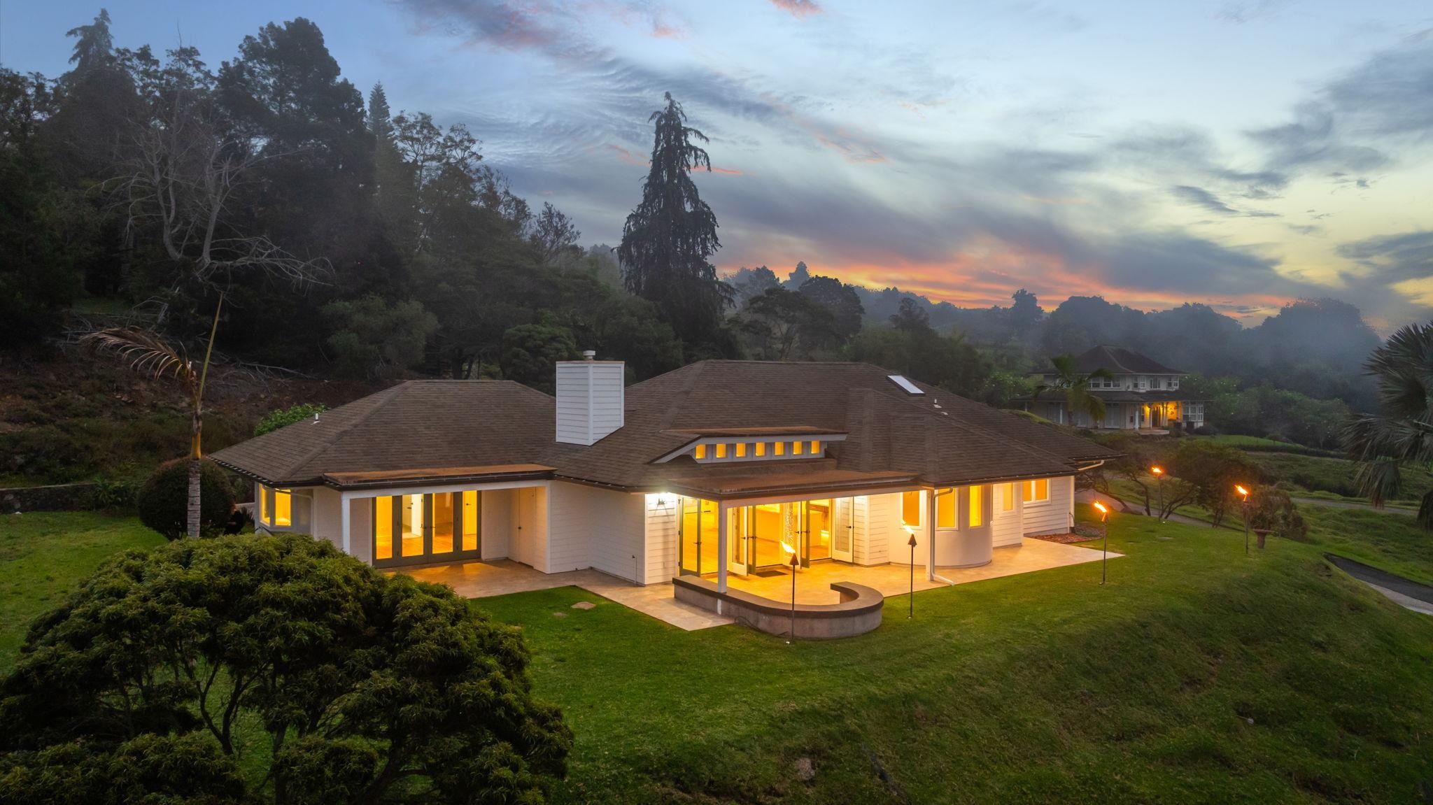 a view of a big house with a big yard and large trees