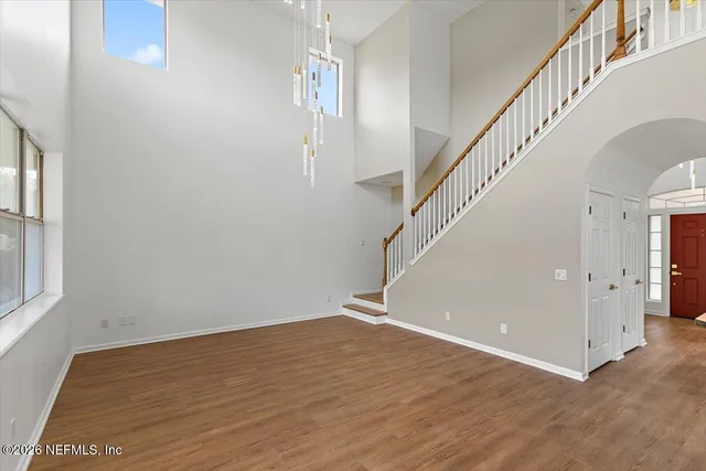a view of an empty room with wooden floor and stairs