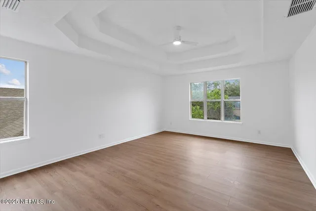 an empty room with wooden floor and windows