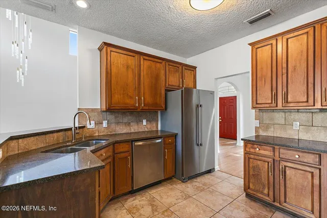 a kitchen with stainless steel appliances granite countertop a refrigerator and wooden cabinets