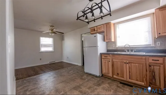 a kitchen with stainless steel appliances granite countertop a refrigerator a sink dishwasher a stove and white cabinets with wooden floor