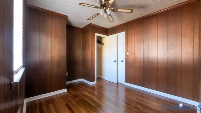 an empty room with wooden floor and fan