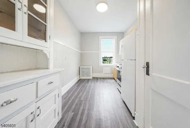 a view of a kitchen with white cabinets and wooden floor