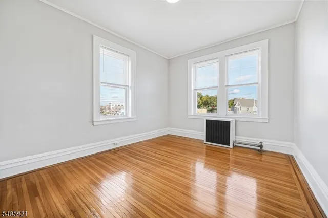 an empty room with wooden floor cabinet and windows