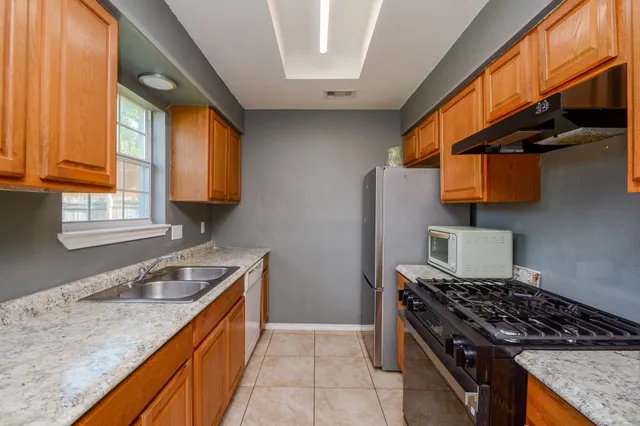 a kitchen with granite countertop a sink a stove and cabinets
