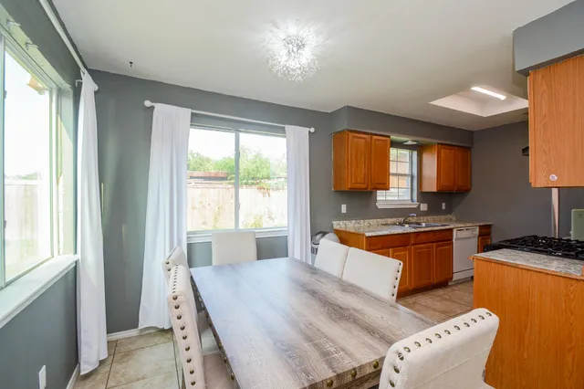 a kitchen with stainless steel appliances granite countertop a stove a sink a refrigerator white cabinets and wooden floor