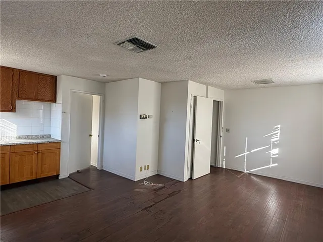 a view of an empty room and a kitchen