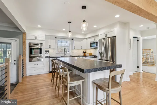a kitchen with stainless steel appliances a dining table chairs refrigerator and microwave
