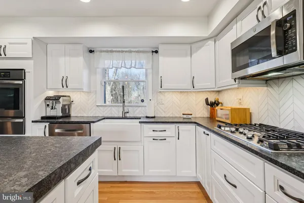 a kitchen with stainless steel appliances granite countertop a stove a sink and a microwave