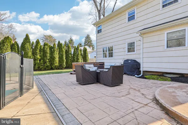 a view of a patio with couches chairs and a fire pit with two large trees