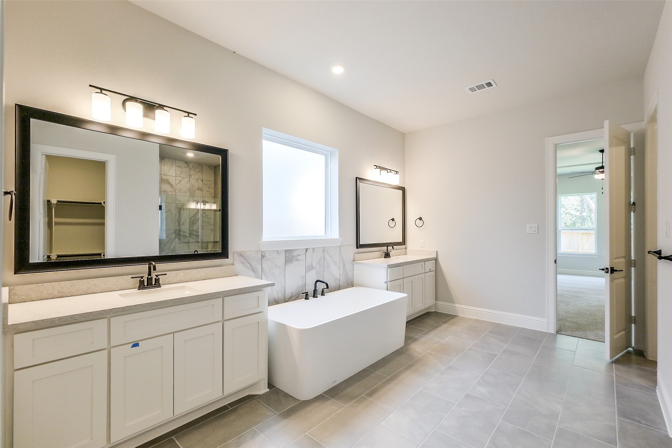 12965 Whitewater Way Conroe, TX 77302 - Photo 27 of 50 a spacious bathroom with double vanity a mirror and a bathtub