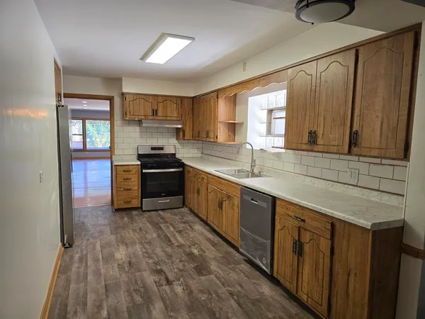 a kitchen with kitchen island granite countertop a sink cabinets and stainless steel appliances