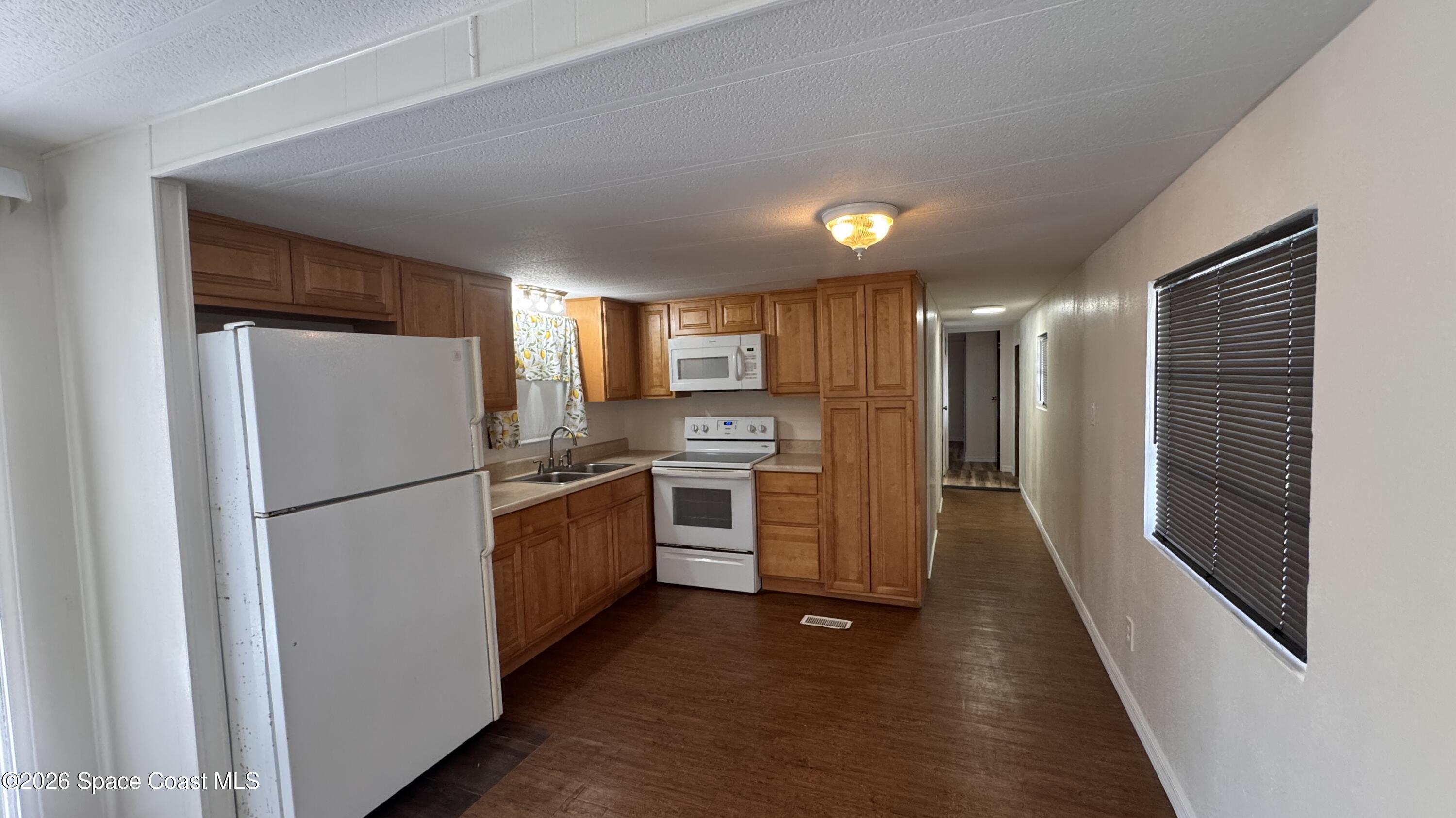 2522 Amberly Road Northeast Palm Bay, FL 32905 - Photo 3 of 13 a kitchen with stainless steel appliances a refrigerator a sink and wooden floor